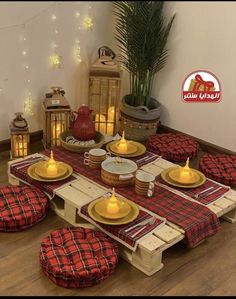 the table is set with red and black plaid cloths, yellow plates and candles