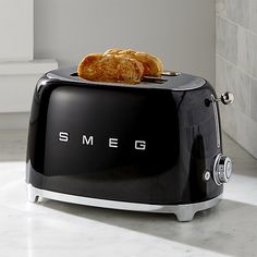 two pieces of toast sitting on top of a black toaster with the word smeg written on it