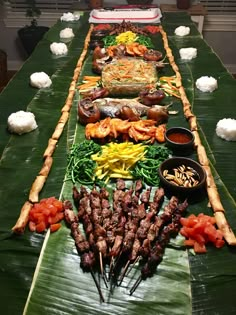 a man standing in front of a long table filled with skewered meats and vegetables