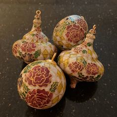 four decorative ornaments are sitting on the table top, one is red and yellow with green leaves