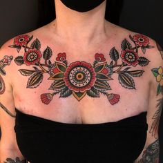 a woman with tattoos on her chest wearing a face mask