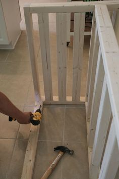 a person holding a drill and hammer in front of a wooden gate that has been built into the floor