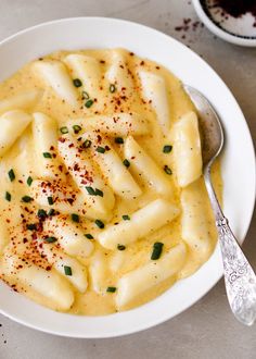 a white bowl filled with macaroni and cheese next to a cup of coffee