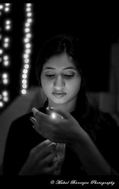 a woman is looking at her cell phone in the dark with some lights behind her