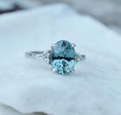 an oval cut aquamarinee and diamond ring sitting on top of a white cloth