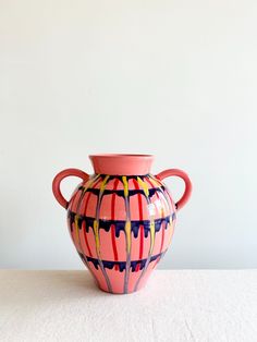 a pink vase sitting on top of a white table