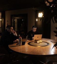 two men sitting at a table with laptops