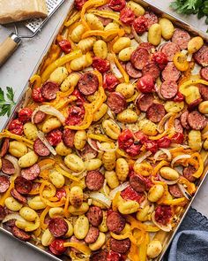 a pan filled with sausage, potatoes and tomatoes