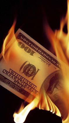 a hundred dollar bill on fire with black background