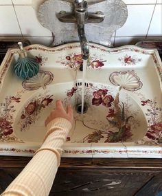 a person is washing their hands in a sink with floral designs on the bottom and sides