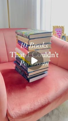 a stack of books sitting on top of a pink couch