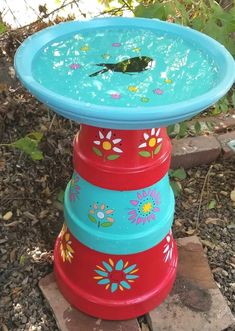 three colorful bowls stacked on top of each other in the grass with flowers painted on them