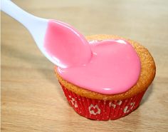 a cupcake with pink icing on it and a spoon sticking out of it