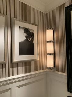 a bathroom with striped wallpaper and two framed pictures on the wall next to it