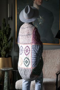 a person with a hat on their head standing in front of a couch and painting