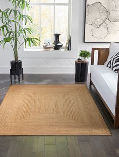 a living room with white walls and wood flooring on the wooden floor, along with a large rug