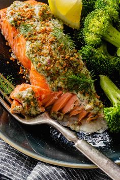 a plate with salmon, broccoli and lemon wedges next to a fork