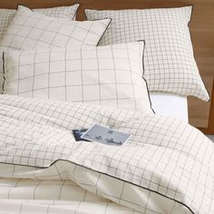 an unmade bed with white sheets and black checkered comforter on the headboard