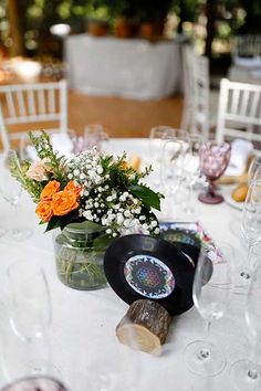 the table is set with wine glasses, flowers and an old vinyl record on it