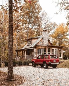 a red pick up truck parked in front of a log cabin on a gravel road