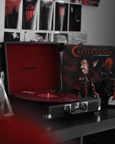 a red record player sitting on top of a wooden table next to a vinyl album