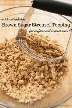 a glass bowl filled with brown sugar on top of a wooden table next to a metal spatula