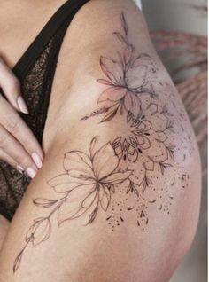 a close up of a woman's thigh with tattoos on it and flowers in the middle