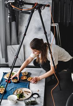 a woman is preparing food on a table in front of a camera set up for filming