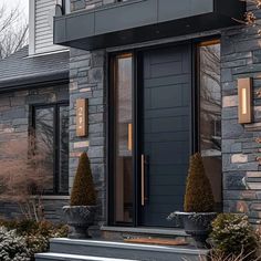 a black front door with two planters on each side and an entry way leading into the house