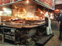 a man standing in front of a large grill filled with food