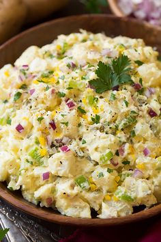 a wooden bowl filled with potato salad on top of a table