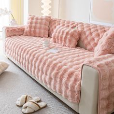 a pink couch with pillows and slippers on the floor