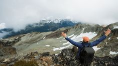 a man standing on top of a mountain with his arms wide open and hands in the air