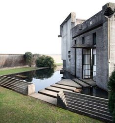 an old building with steps leading up to it and a pond in the foreground