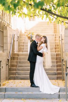 a bride and groom kissing on the steps