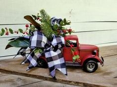 an old red truck is decorated with greenery and ribbon for the front door or porch