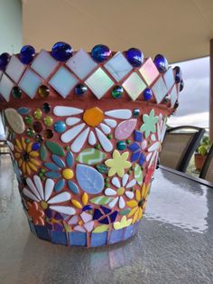 a colorful glass vase sitting on top of a counter next to a window sill