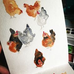 a person holding up a piece of paper with different colored chickens on it and one chicken in the middle