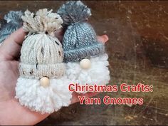 someone is holding three small crocheted christmas hats with pom - poms