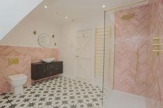 a bathroom with pink and gold tiles on the floor, shower stall and sink area