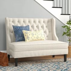 a white couch sitting under a stair case next to a blue and white rug on top of a wooden floor