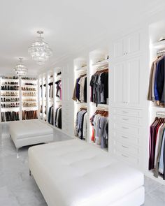 a walk in closet filled with lots of white furniture and shelves full of clothes on hangers