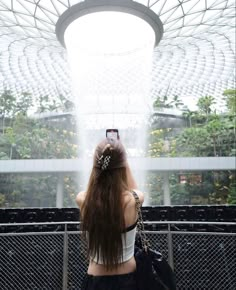 a woman taking a photo with her cell phone in front of an indoor dome structure