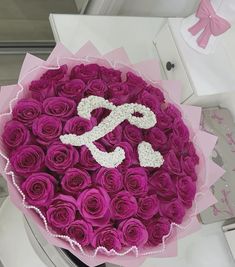 a large bouquet of purple roses with the letter s on it's center piece