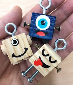 three wooden keychains with faces on them in the shape of eyes and mouths