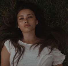 a woman laying on the ground with her hair blowing in the wind and eyes closed