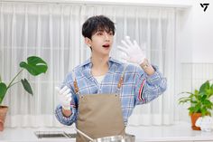 a young man in an apron is making something with his hands while standing next to a pot