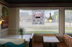 the inside of a restaurant with tables, benches and a sign on the window that says drive thru open