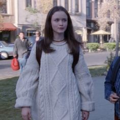 two people walking down the street in front of some buildings