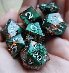 green and gold marbled dice with numbers on them in the palm of someone's hand